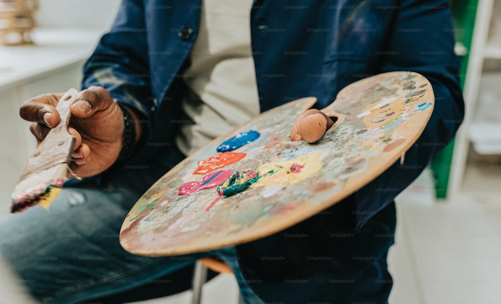 a man holding a paintbrush and a painting board