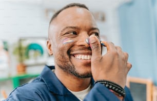 a man smiles while holding a cell phone to his ear