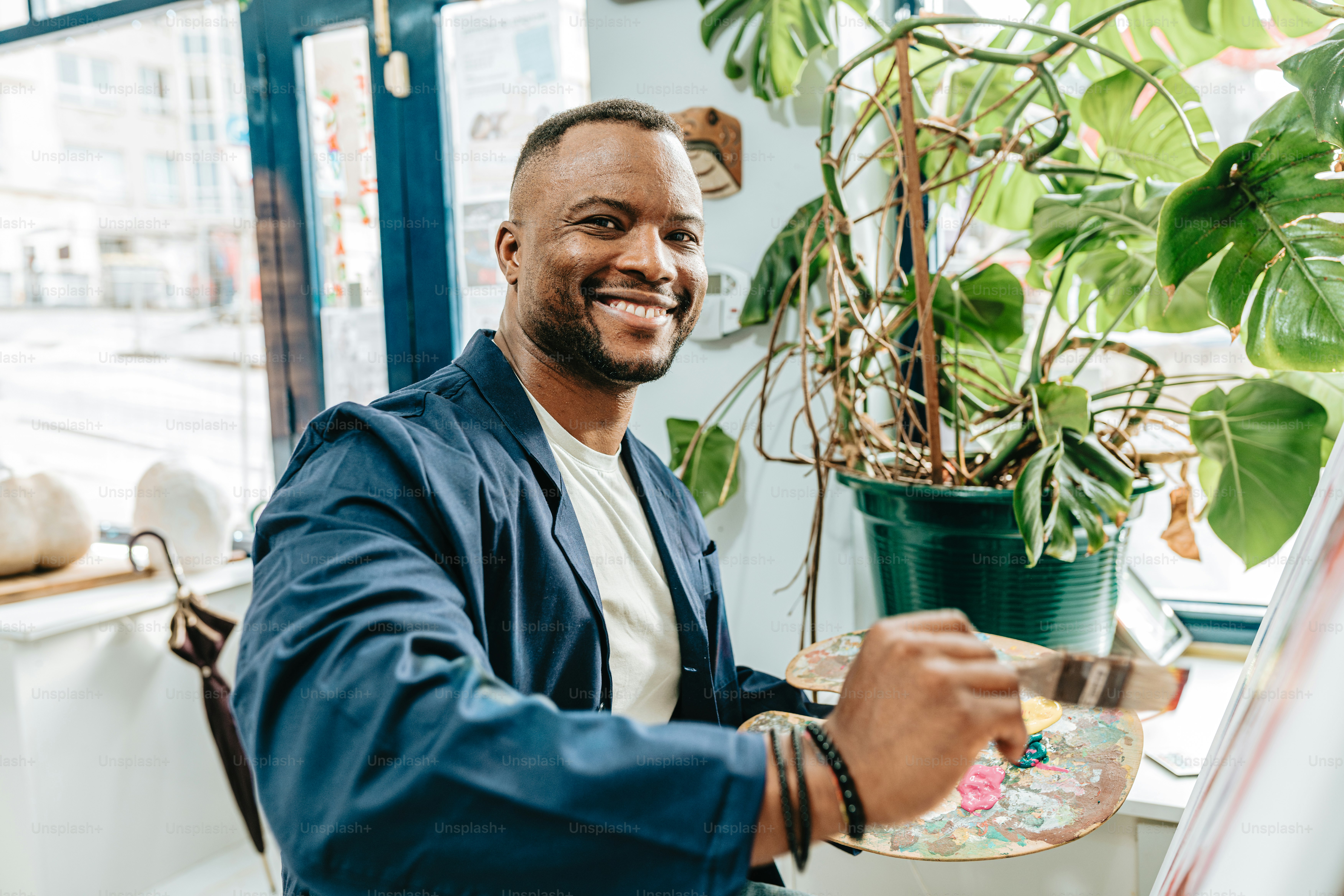 a man is smiling while holding a paintbrush