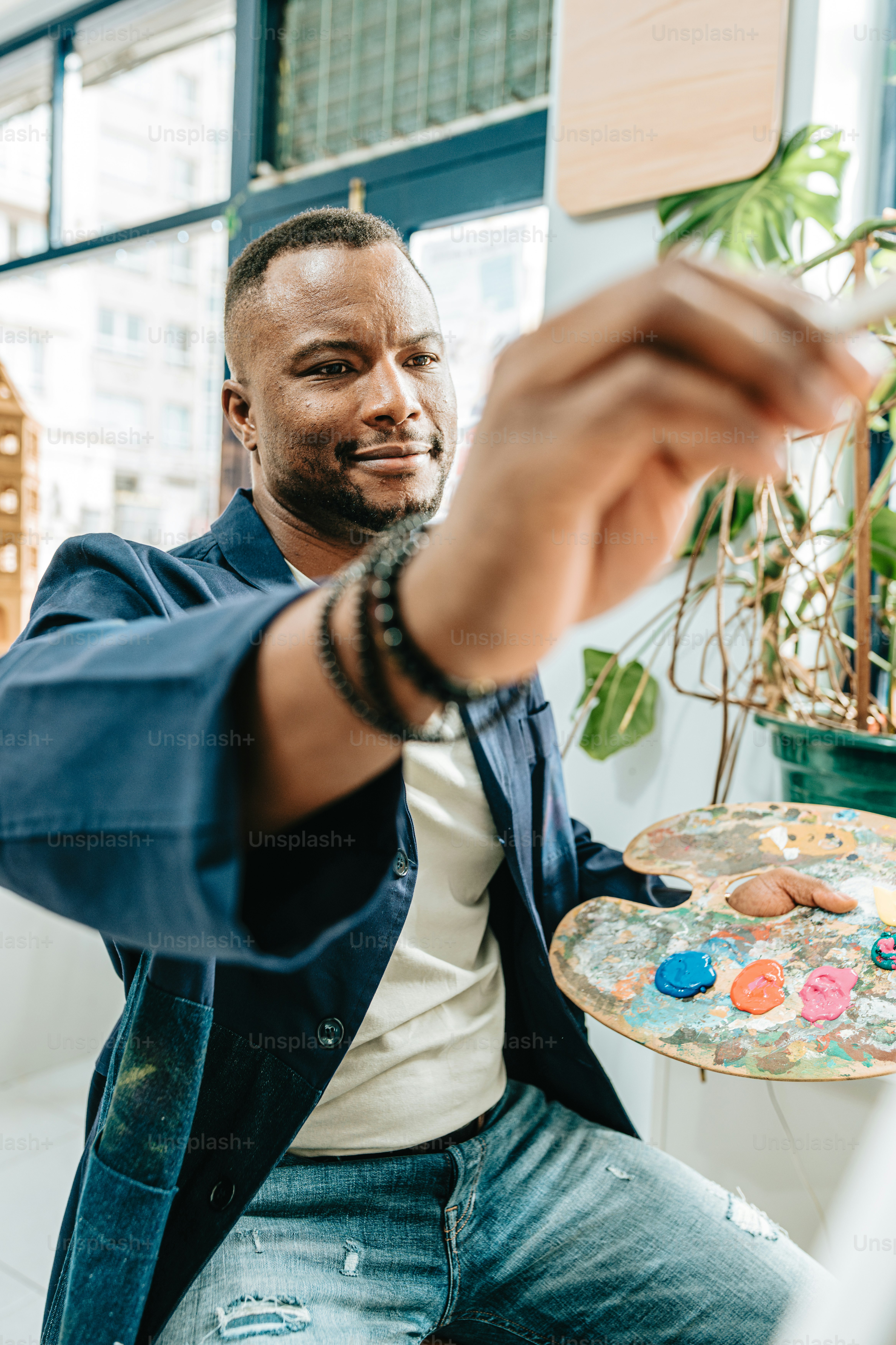 a man sitting at a table holding a paintbrush