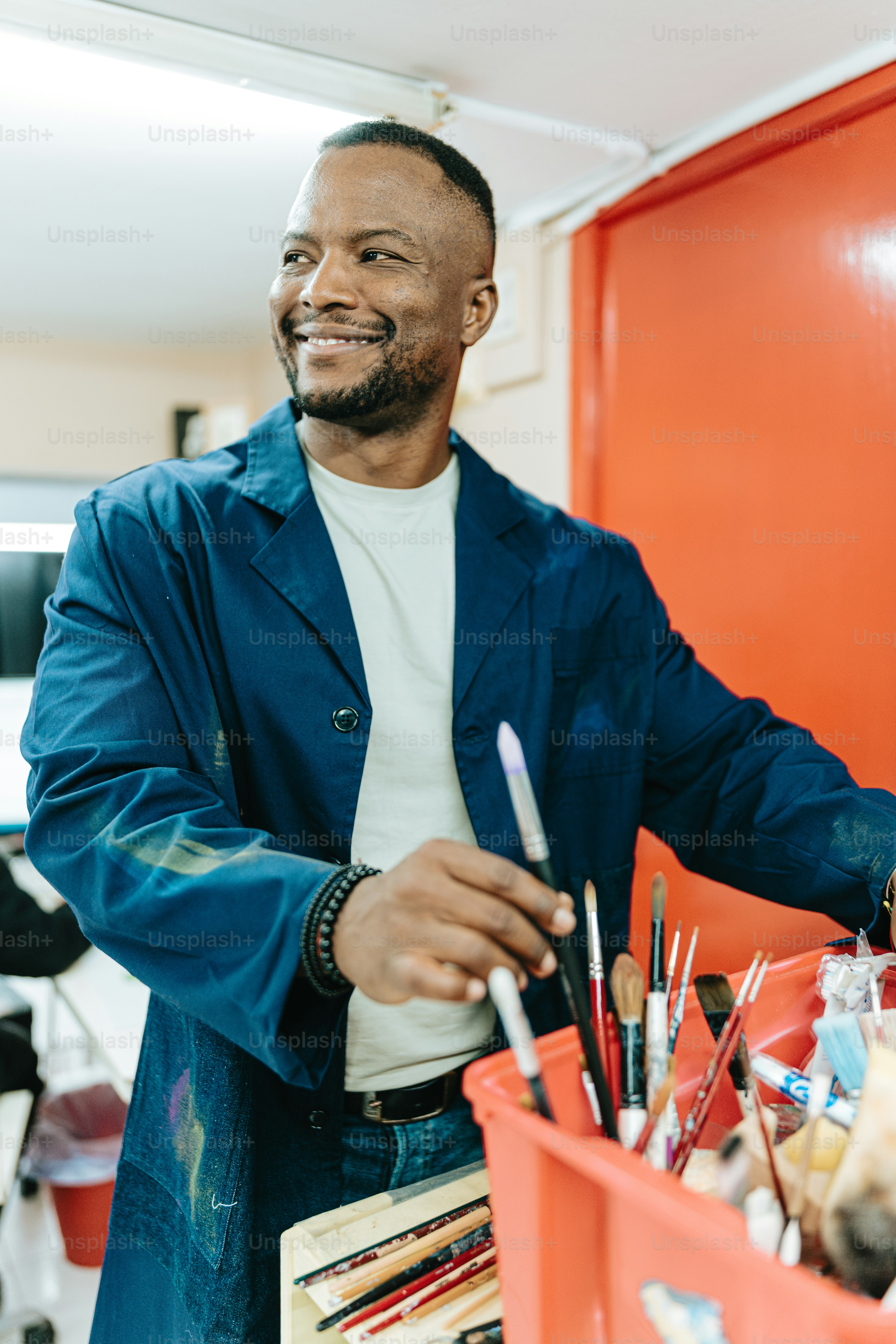 a man is smiling while holding a paintbrush