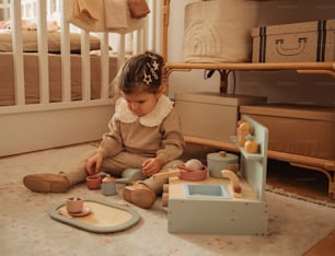 a little girl sitting on the floor playing with her toys