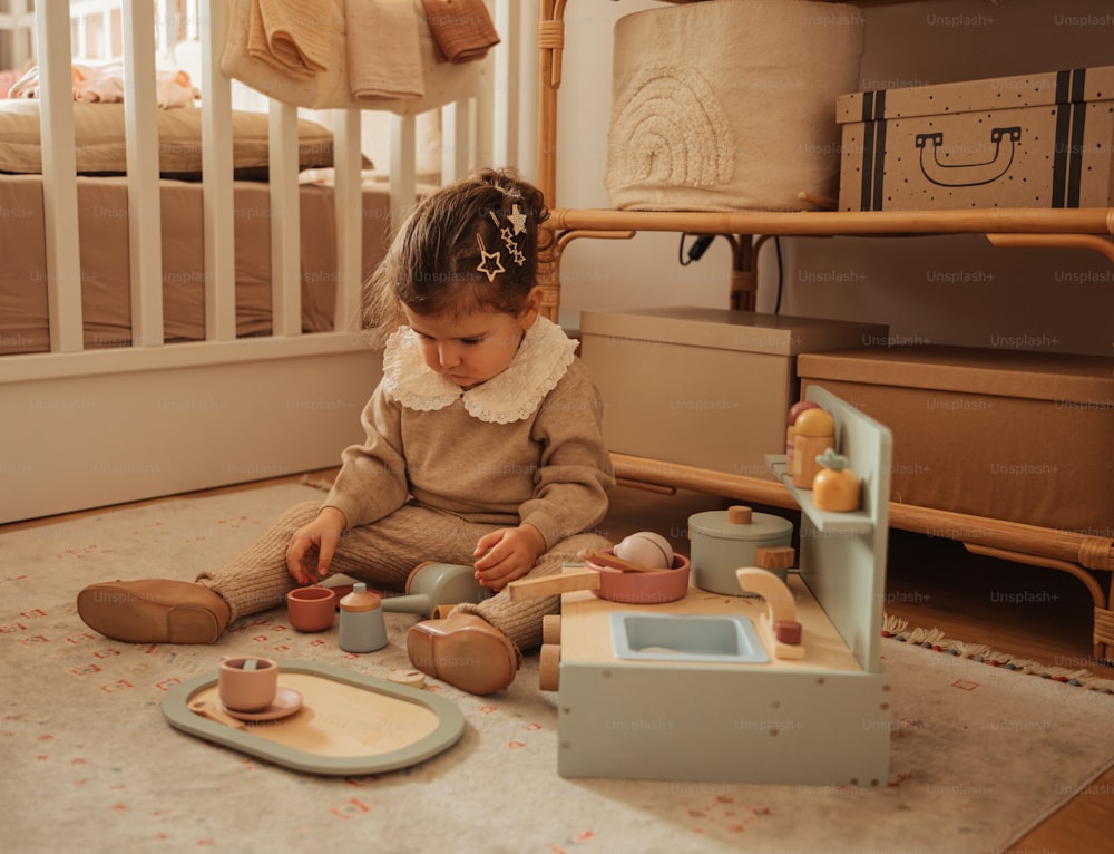 una bambina seduta sul pavimento che gioca con i suoi giocattoli