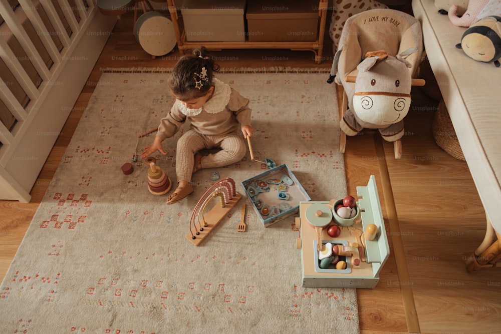 a little girl sitting on the floor playing with toys