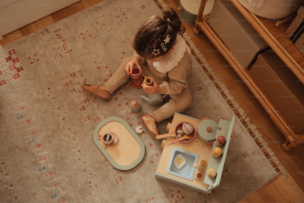a little girl sitting on the floor playing with toys