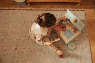 a little girl playing with a toy kitchen set