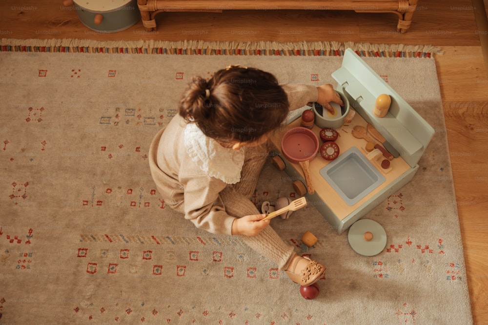 a little girl playing with a toy kitchen set