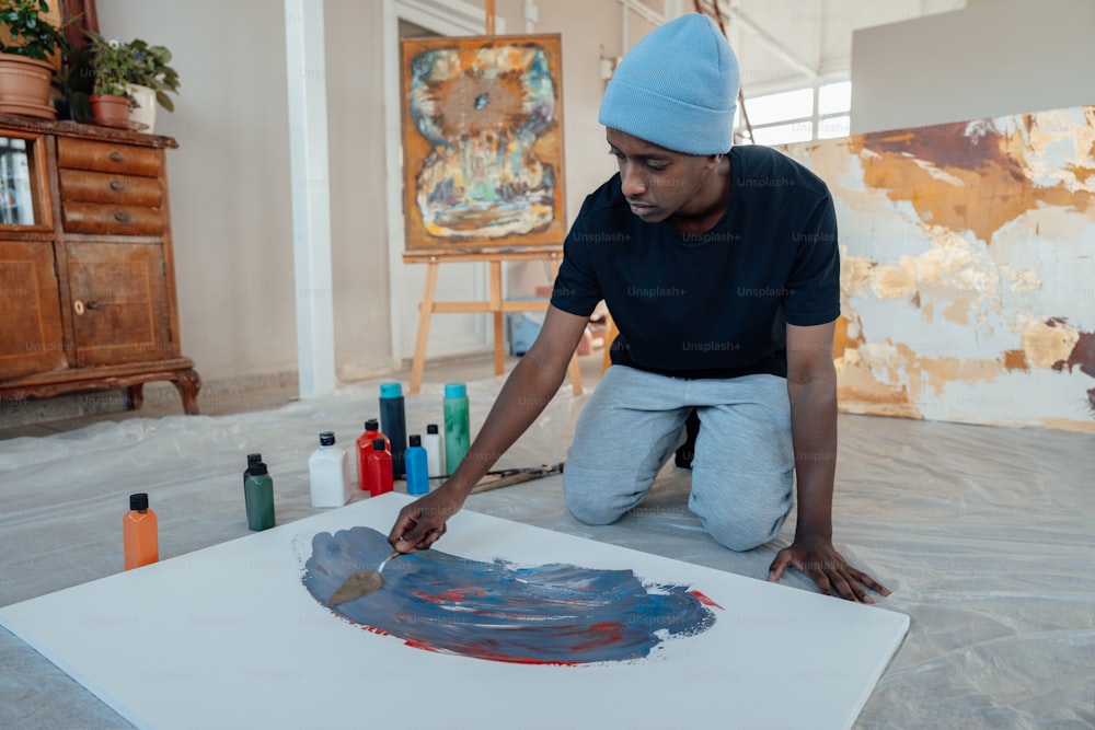 a man in a blue hat is painting on a canvas