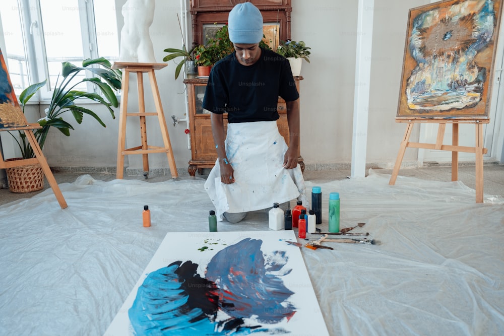 Un hombre con un sombrero azul está pintando un cuadro