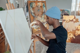 a man in a blue hat painting on a canvas