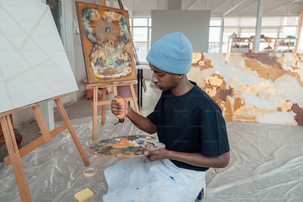 un hombre en un sombrero azul pintando en un lienzo