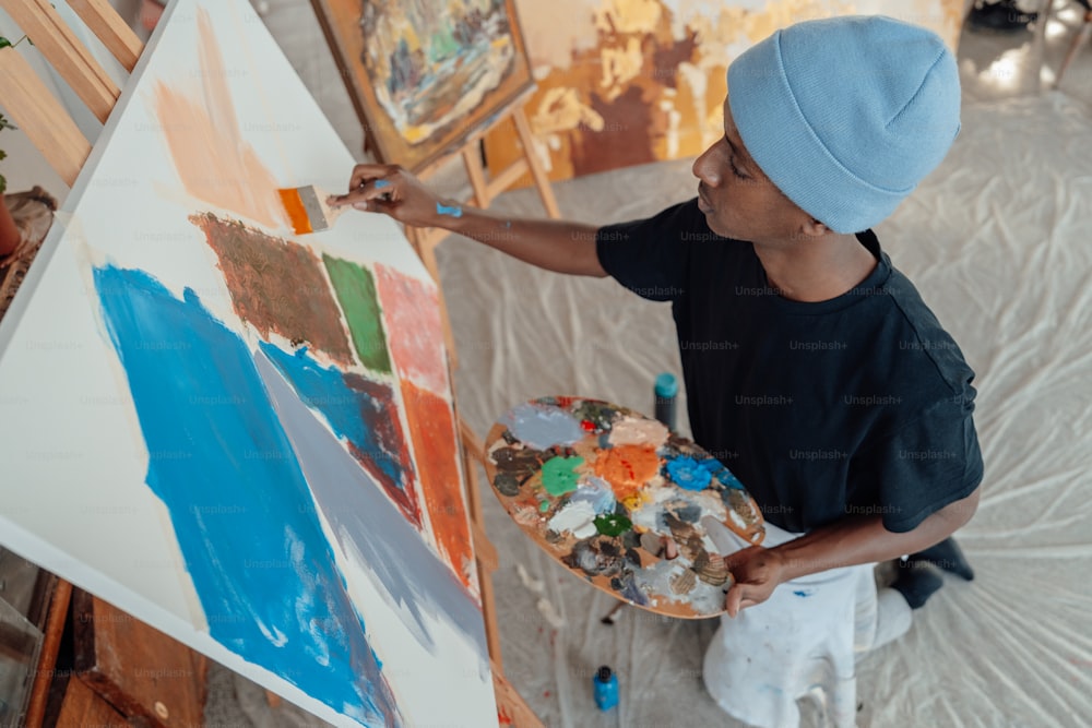 a young boy is painting on a canvas