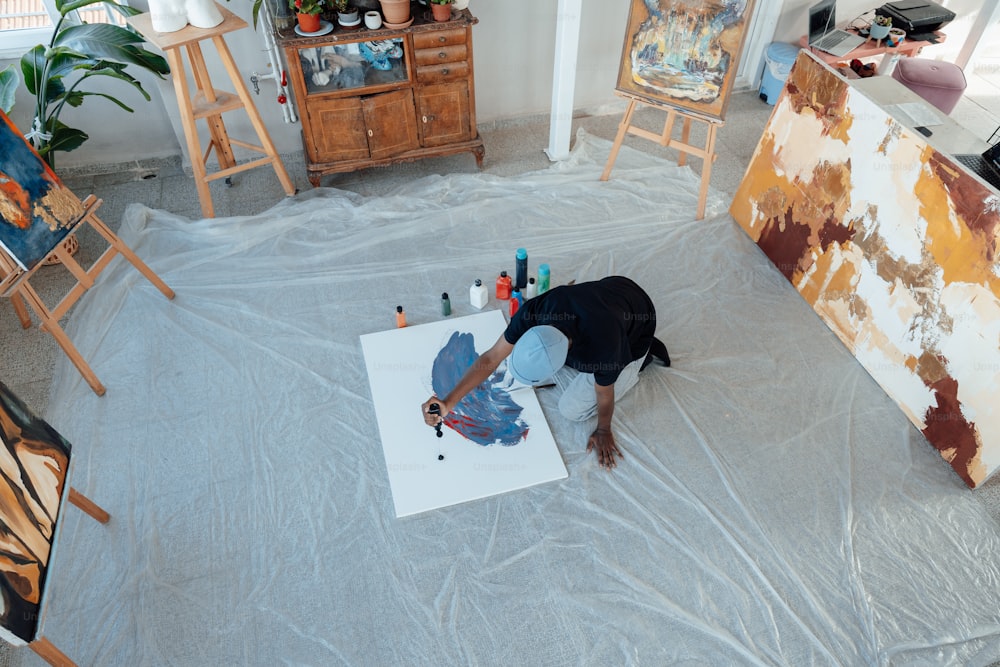 uma pessoa deitada no chão em frente a uma pintura