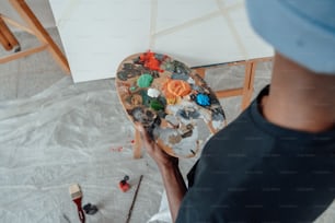 un homme peint un tableau sur un chevalet en bois