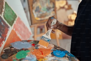 a person holding a paintbrush and painting on a canvas