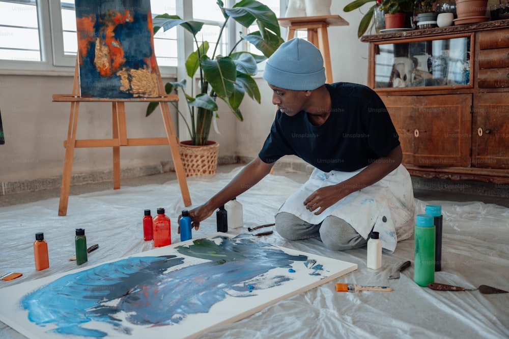 um homem sentado no chão pintando um quadro