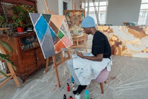 ein Mann sitzt vor einem Gemälde auf einer Staffelei
