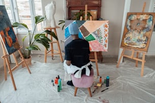 a man sitting on a stool in front of paintings