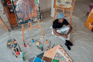 a man sitting on the floor in front of paintings