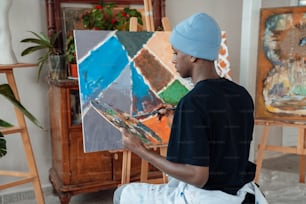 um homem sentado em frente a uma pintura em um cavalete