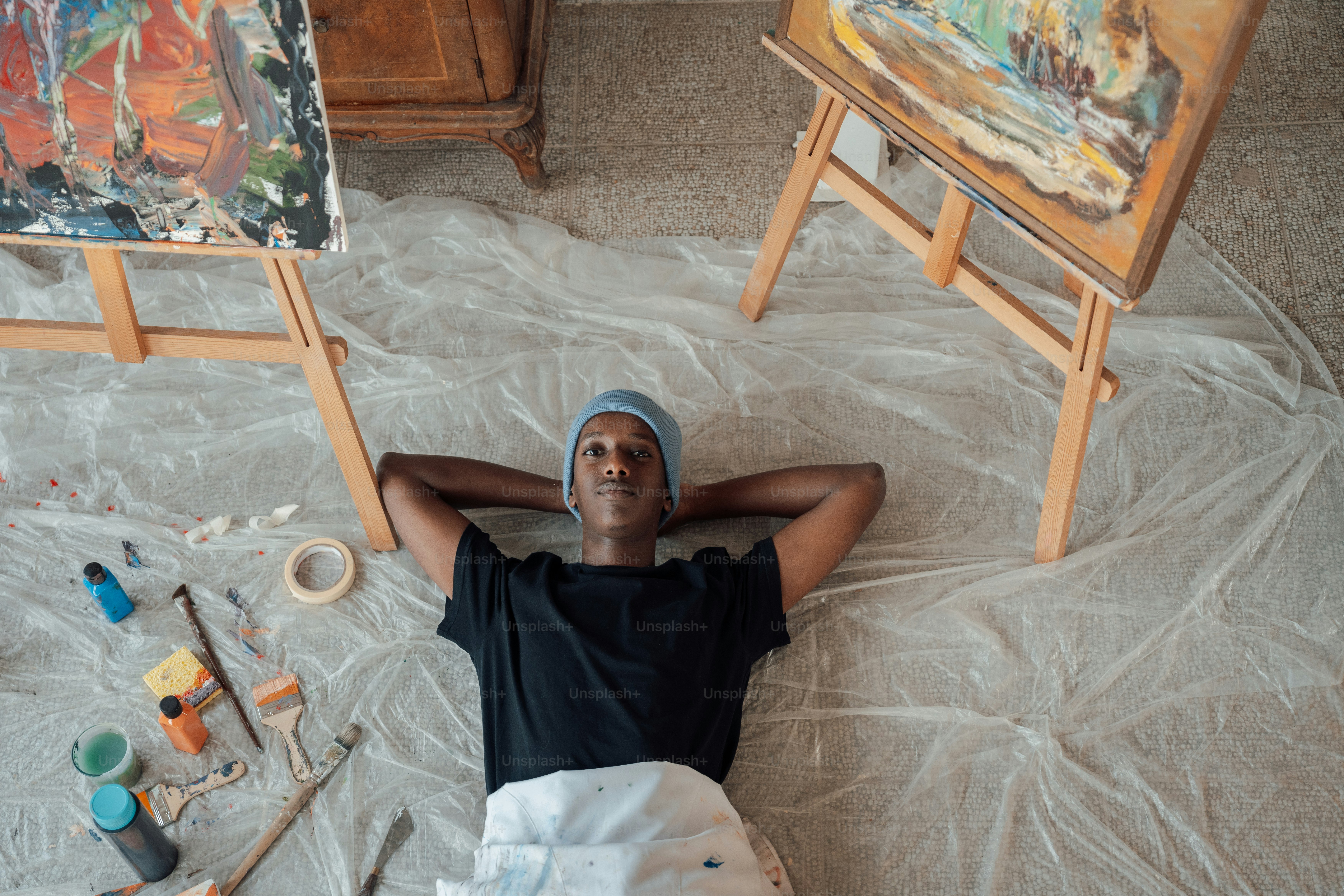 a man laying on the floor in front of paintings