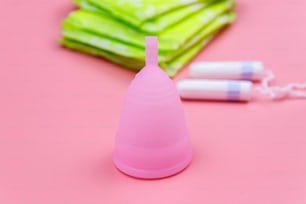 Assorbente, tamponi e coppetta mestruale su sfondo rosa. Concetto di giorni critici, mestruazioni, igiene femminile