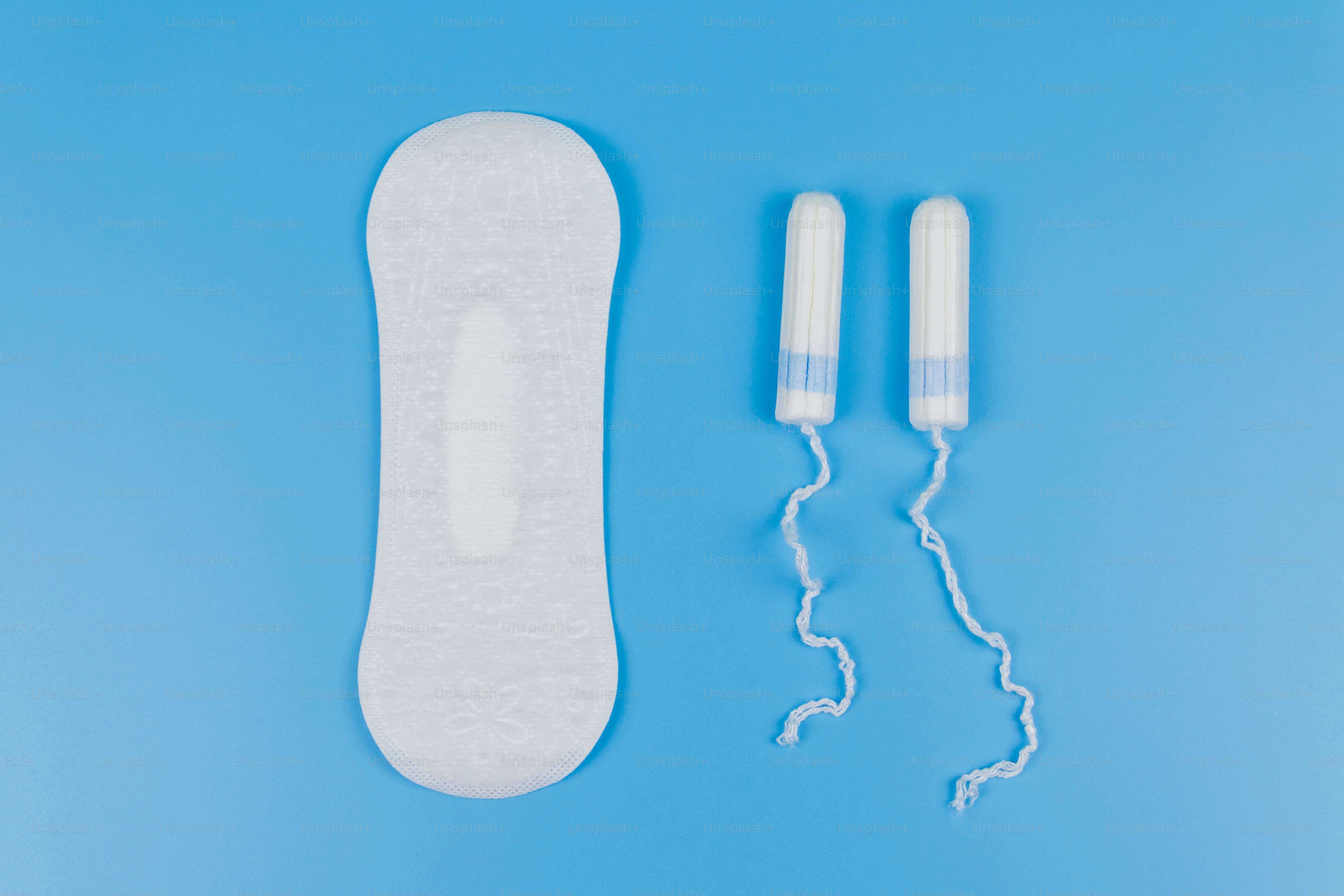 Sanitary pad and tampons on blue background. Top view