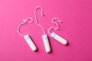 Three tampons on pink background, top view