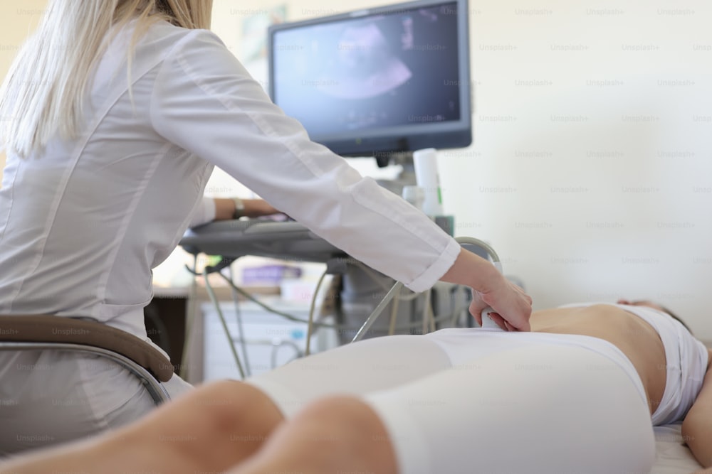 Arzt macht Ultraschalluntersuchung der Beckenorgane an einer Frau in Nahaufnahme. Instrumentelle Diagnostik des Frühschwangerschaftskonzepts