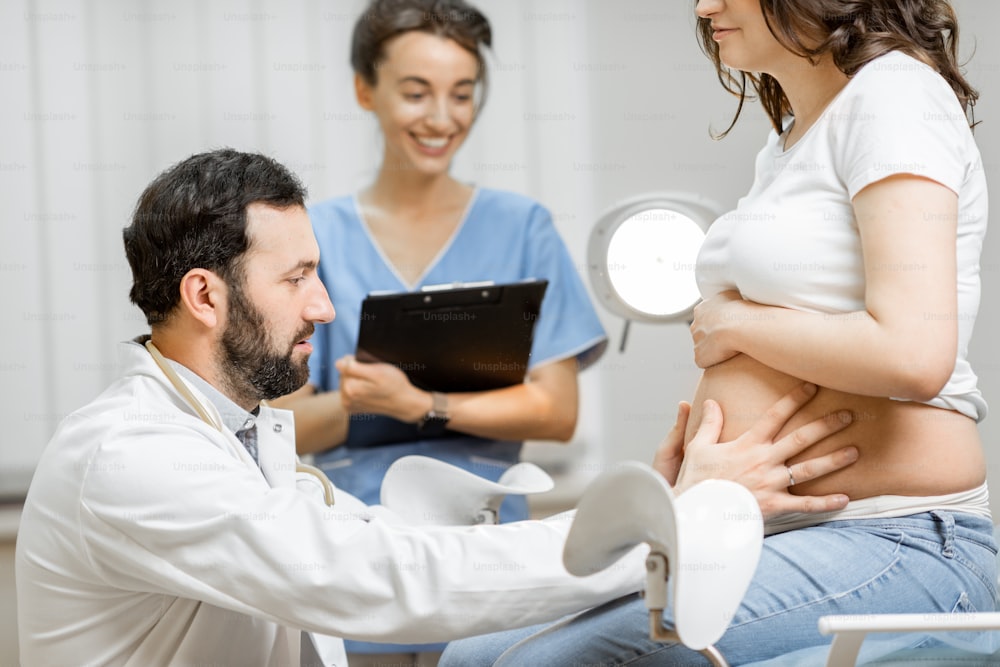 Médecin avec une infirmière lors de l’examen médical d’une femme enceinte au bureau. Concept de soins médicaux et de santé pendant la grossesse