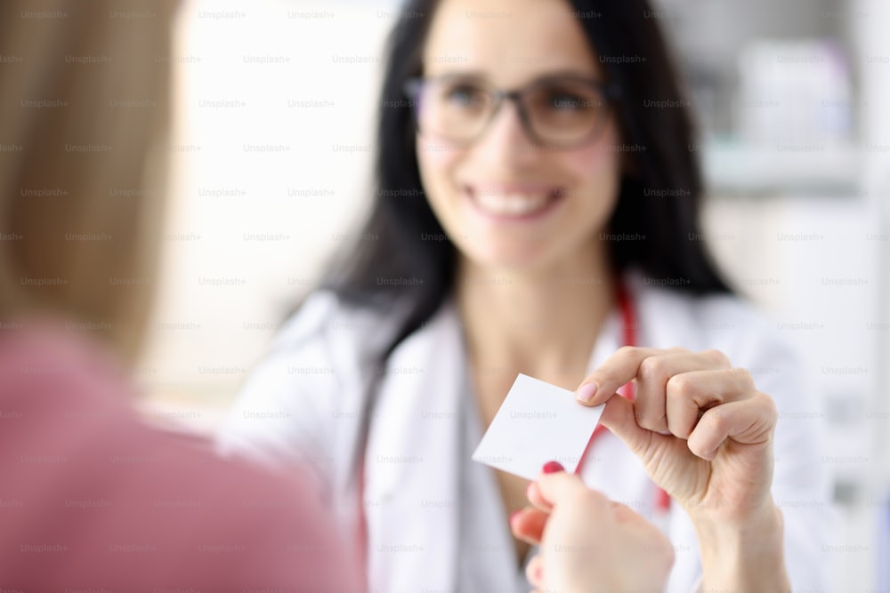 Doctor hands over business card to patient in office. Medical business card concept