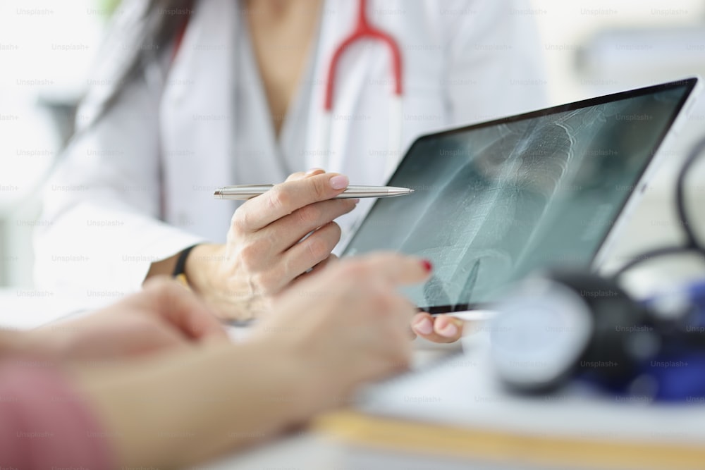 Doctor shows patient an x-ray of lungs on tablet. Lung inflammation and pneumonia concept