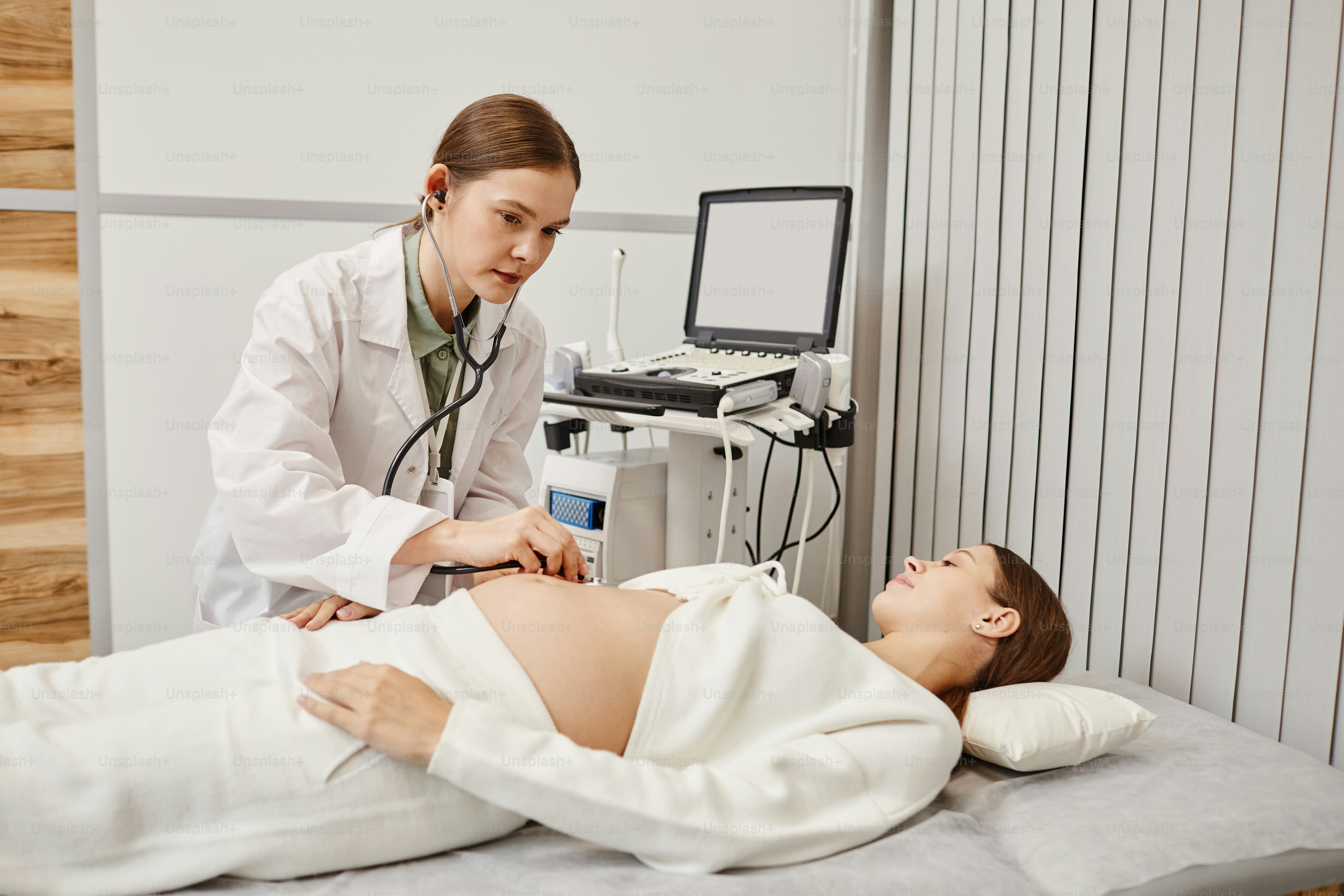 Ritratto di medico femminile che esamina la giovane donna incinta nella stanza dell'ecografia presso la clinica medica