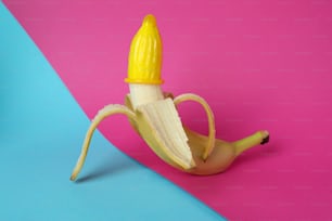 Banana with yellow condom on two tone background