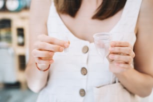 Woman hands holding menstrual cup and tampons. Different types of feminine period items. Woman chooses modern alternative reusable female supplies for intimate hygiene in zero waste shop