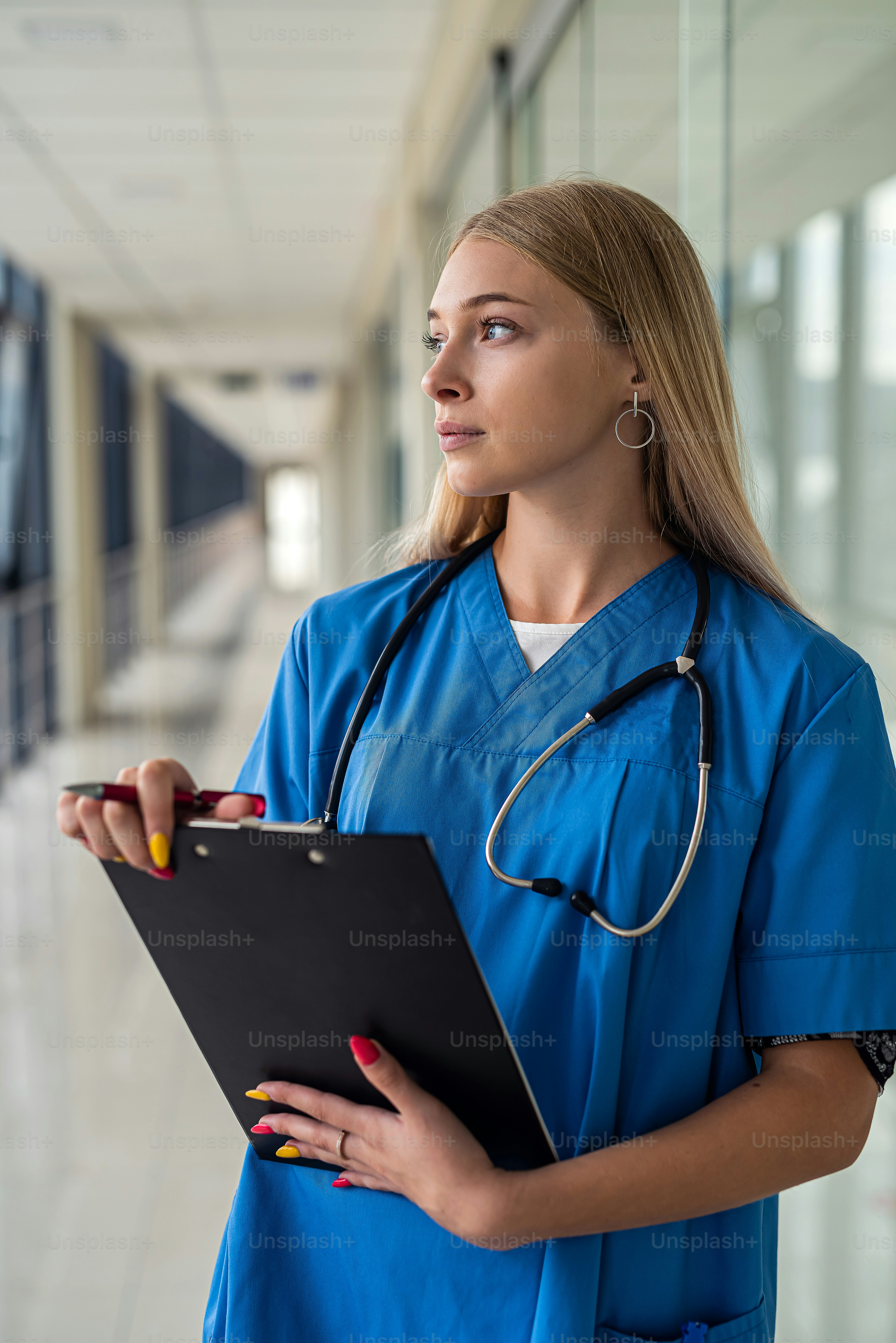Young beautiful nurse with a stethoscope around her neck and a tablet ...