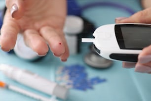 Close-up of doctor check blood sugar level of client use digital glucometer at hospital. Diabetes test for patient on appointment. Medicine, clinic concept