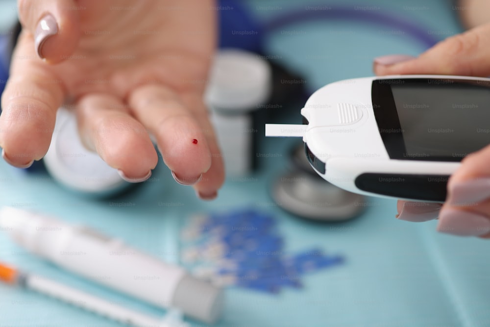 Primo piano del medico controlla il livello di zucchero nel sangue del glucometro digitale di uso del cliente in ospedale. Test del diabete per il paziente su appuntamento. Medicina, concetto di clinica