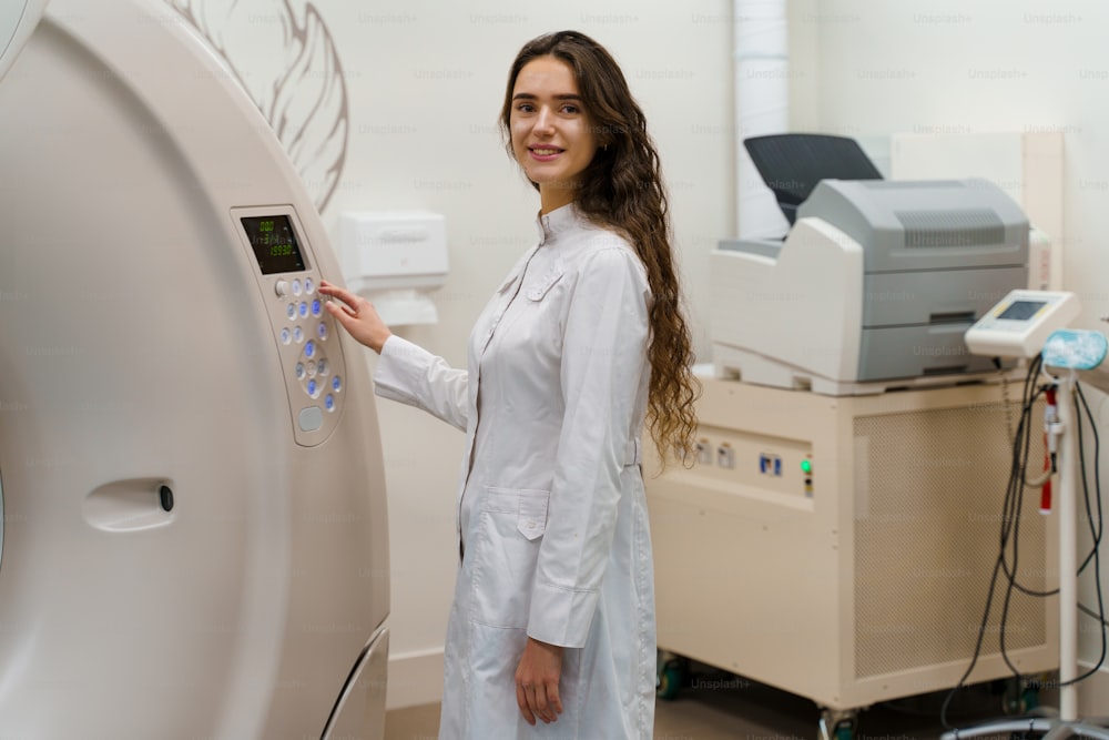 Médico faz tomografia computadorizada para paciente. Menina no casaco branco olha na câmera e pressione o botão no CT