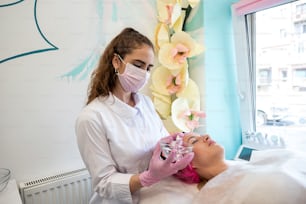 Una cosmetóloga calificada prepara la piel del cliente para la aplicación de la mascarilla. El concepto de procedimientos de belleza. salón de belleza. Mascarilla
