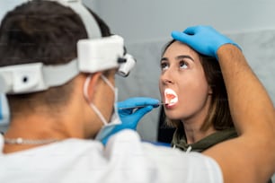 Ein HNO-Arzt mit Maske untersucht die Halsschmerzen eines Patienten in der Praxis. Medizin. Überprüfung der Drüsen