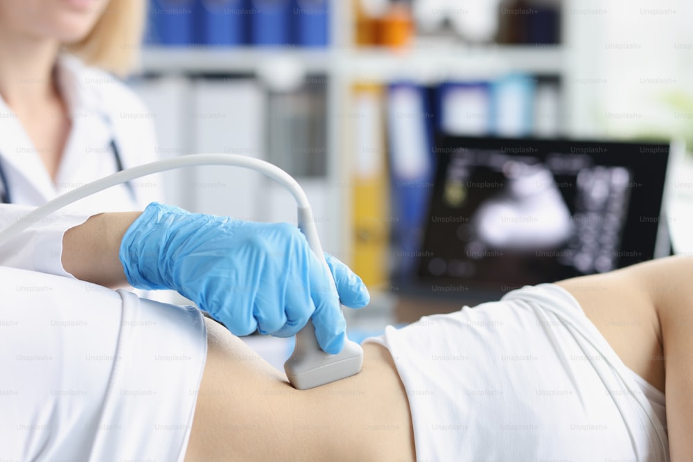 Gros plan d’un travailleur médical professionnel examinant le corps des clients avec un outil d’échographie. Femme enceinte en examen de santé planifié. Médecine, scanner, concept clinique