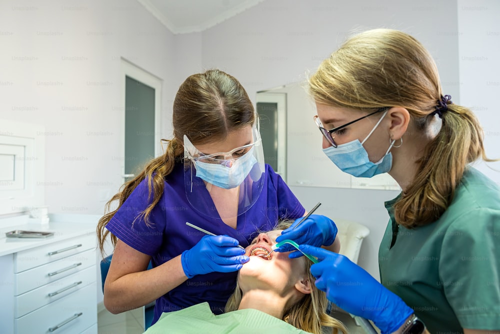 치과 진료소에서 성인 환자의 치아를 치료하는 거울, 드릴 및 치과 공기 물총 스프레이를 사용하는 치과 의사