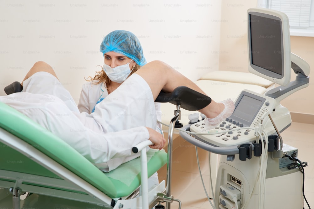 Gynecologist preparing for an examination procedure for a woman sitting on a gynecological chair