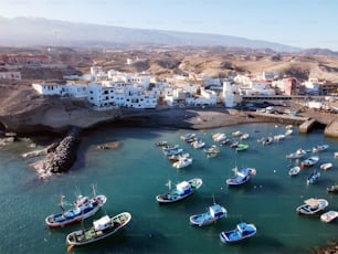 Veduta aerea di un piccolo villaggio di pescatori con alcune barche colorate a Tajao, Tenerife, Isole Canarie. Filmati 4k di alta qualità
