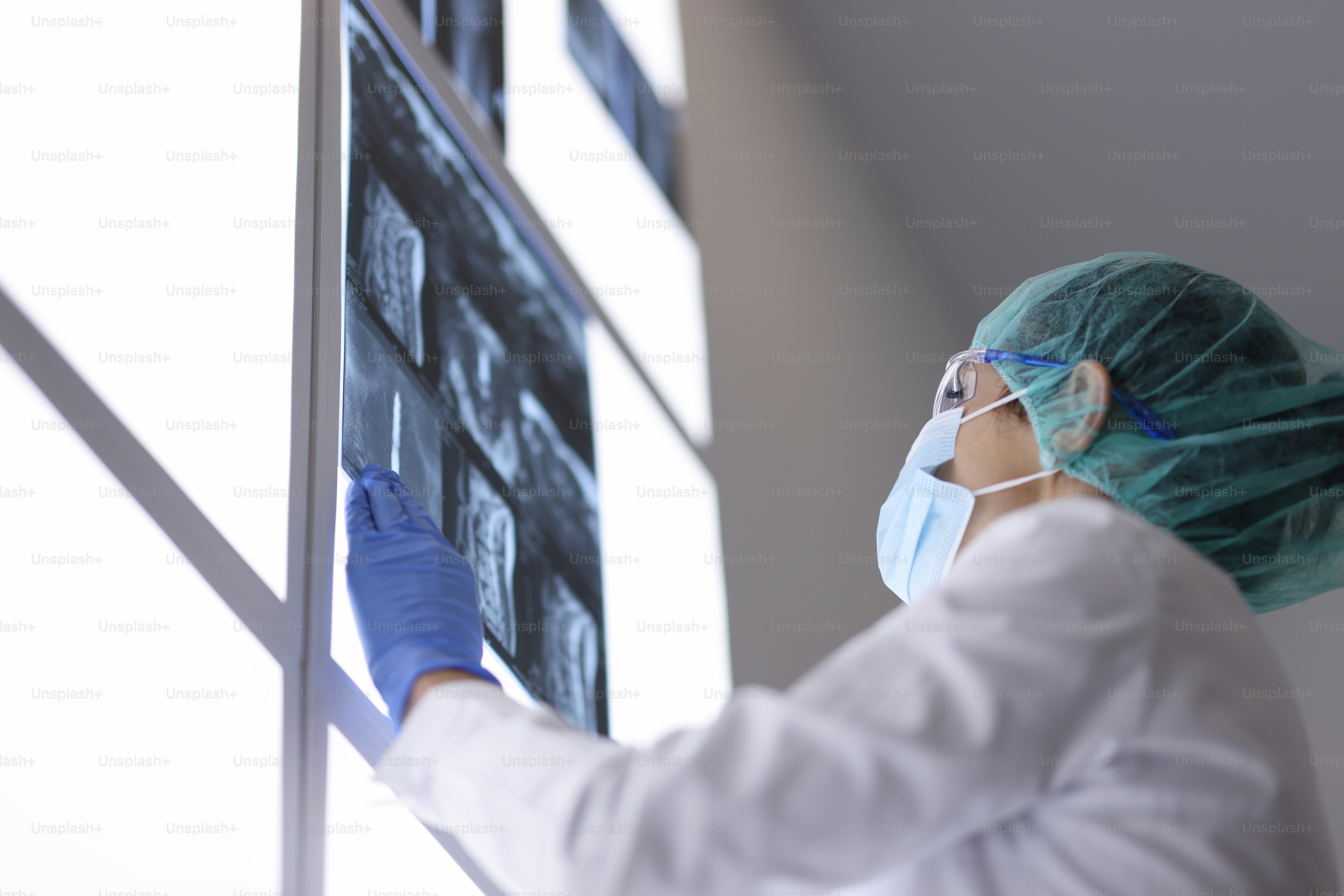 Arzt mit medizinischer Maske in der Praxis untersucht ein Röntgenbild. Untersuchung von Patienten mit Anzeichen des Coronavirus Konzept