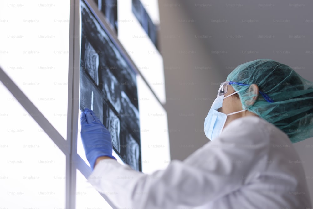 Un médecin portant un masque médical dans son cabinet examine une radiographie. Examen des patients présentant des signes de coronavirus concept