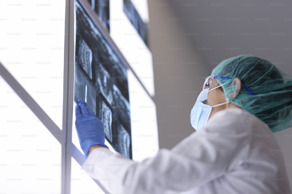 Doctor with medical mask in office examines an X-ray. Examination of patients with signs of coronavirus concept