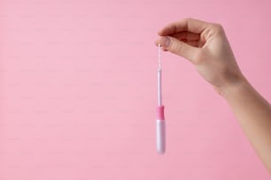 Isolated on the pink background photo of a tampon in hand of woman. Website banner