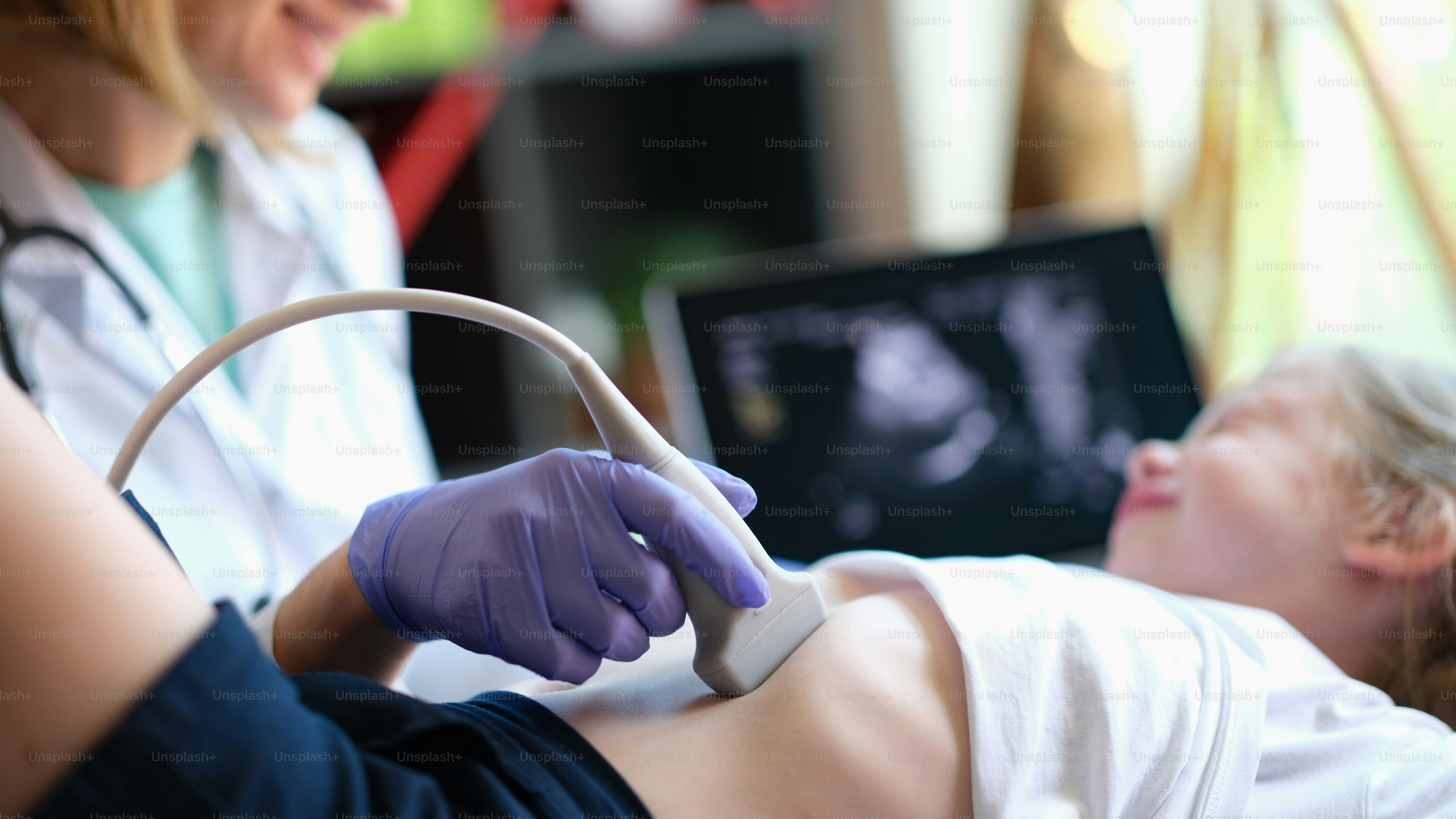 Doctor conducting ultrasound examination of internal organs of child in clinic. Diagnosis and treatment of diseases of liver and biliary tract in children concept